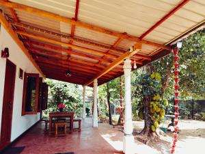 a wooden pergola with a table and a tree at Canal Resort Udawalawa in Ratkarawwa