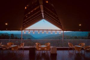 a group of tables and chairs on a balcony with a view at Omaya Vista in Mukteshwar