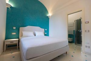 a bedroom with a white bed and a blue wall at Borgo Sant'Anna in Amalfi