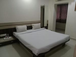 a large white bed with two pillows on it at Hotel Paras in Junagadh
