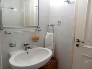 a white bathroom with a sink and a mirror at Family Booklovers space in Aigio +11 photos