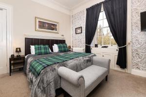 a bedroom with a bed and a chair and a window at Dunfallandy House Hotel in Pitlochry +47 photos