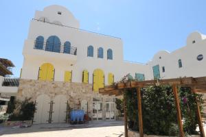 a large white building with yellow doors and windows at Klodian Durmishi in Vlorë