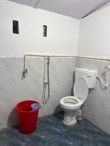 a bathroom with a toilet and a red bucket at Jumusing homestay in Rupa
