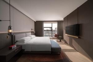 a hotel room with a bed and a television at 苏州云启一方酒店-凯悦尚选 in Suzhou