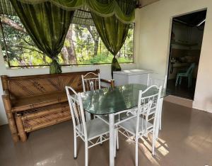 a dining room with a table and chairs and a window at Penoria's lodge kubo in Mambajao