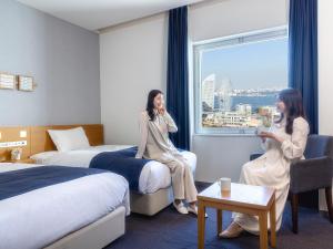 two women sitting in a hotel room looking out the window at Yokohama Sakuragicho Washington Hotel in Yokohama