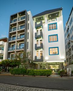 a white building with blue windows on a city street at Samann Blue in Hulhumale