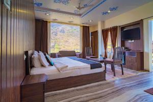 a bedroom with a large bed and a large window at BADIGARH RESORT - Udaipur in Thūr