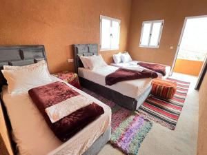 a room with three beds in a room with windows at Pergolas Tamakoucht in Ouarzazate