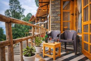 a porch with two chairs and a table with wine glasses at THE CEDAR CASTLE in Mukteshwar