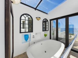 a bathroom with a white tub and windows at The Coastal Crown in Ballito