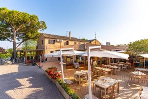 a patio with tables and umbrellas in front of a building at Club del Sole La Risacca Family Collection in Porto SantʼElpidio