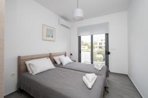 two beds in a bedroom with white walls at Ocean Breeze Residence in Kámpos