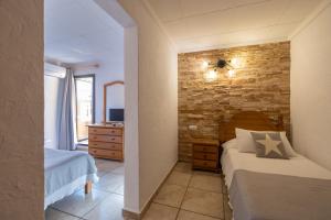 a bedroom with two beds and a stone wall at Hotel Lago Dorado in La Savina