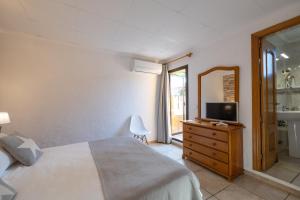 a bedroom with a bed and a television on a dresser at Hotel Lago Dorado in La Savina