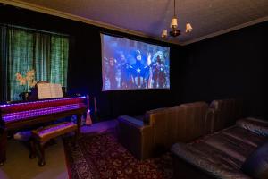 a living room with a piano and a movie screen at Dunfallandy House Hotel in Pitlochry
