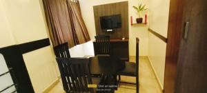 a room with a table and chairs and a television at Theni hotel ramyas in Theni
