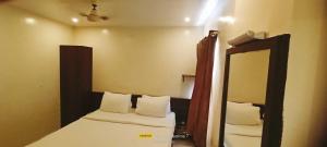 a small bedroom with two beds and a mirror at Theni hotel ramyas in Theni