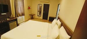 a bedroom with a white bed and a television at Theni hotel ramyas in Theni