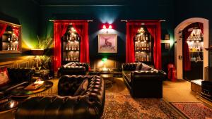 a living room with leather furniture and red curtains at Dunfallandy House Hotel in Pitlochry