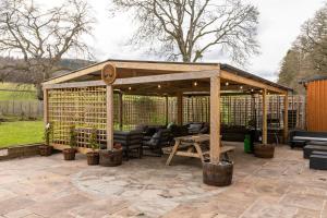 a wooden pavilion with chairs and a table on a patio at Dunfallandy House Hotel in Pitlochry