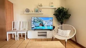 a living room with a flat screen tv on a white stand at Casa Sol e Praia in Porto Santo