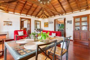 a dining room with a glass table and red chairs at La Paredita Casa Taoro in Tanque