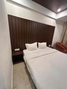 a bedroom with a large white bed with a wooden headboard at Laddu Resort in Bhīm Tāl