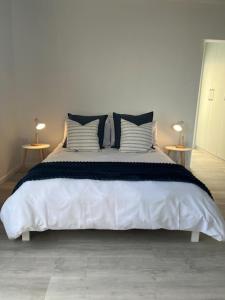 a bedroom with a large bed with four pillows at Net Genoeg in De Kelders