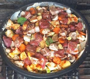 a pan filled with meat and vegetables on a grill at Ramaća House in Ramaća