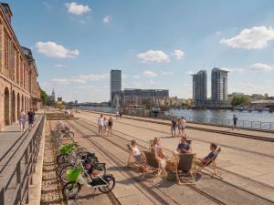people sitting in chairs on a sidewalk next to the water at City-Apartment Spreeufer im Herzen Berlins in Berlin