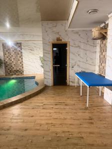 a blue ping pong table in a room with a swimming pool at INFINITY Hotel&Spa in Almaty
