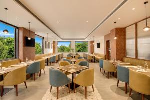 a restaurant with tables and chairs and large windows at Keys Select by Lemon Tree Hotels, Amritsar in Amritsar