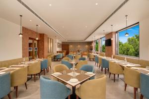 a restaurant with tables and chairs and large windows at Keys Select by Lemon Tree Hotels, Amritsar in Amritsar