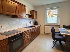 a kitchen with wooden cabinets and a sink and a table at Wasserburg 1 I Familienfreundlich - Ruhig & Erdgeschoss I Parkplatz inkl in Paderborn