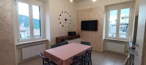 a dining room with a table and two windows at Dimora 99 in LʼAquila