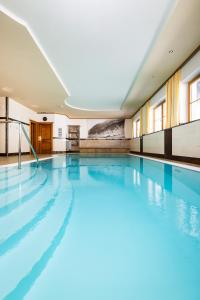 a swimming pool with blue water in a building at Hotel Alpenrose in Zauchensee