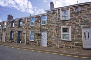 a brick building with white doors and windows on a street at Miners Cottage in Blaenau-Ffestiniog