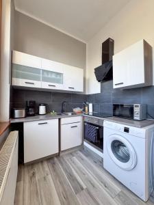 a kitchen with white cabinets and a washer and dryer at City-Apartment Timeless in Berlin
