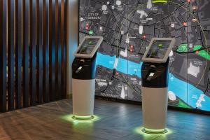 two parking meters in front of a large screen at hub London - Tower Bridge in London