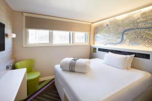 a small room with a bed and a green chair at hub London - Tower Bridge in London