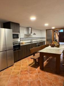 a kitchen with a table and a stainless steel refrigerator at Casa Rural La Font in Sant Mateu