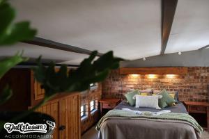 a bedroom with a bed and a brick wall at Olive Branch in Dullstroom