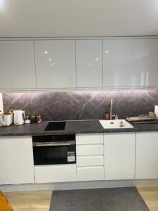 a kitchen with white cabinets and a sink at Brand New One Bedroom Apartment in Hendon +7 photos