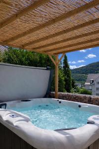 a hot tub on a patio with a wooden pergola at L'Impasse en Duo, appartement cosy 2 personnes avec SPA extérieur privé in Munster