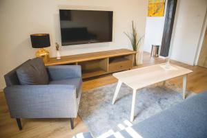 a living room with a tv and a chair and a table at Penzión ÁTRIUM in Prešov +16 photos