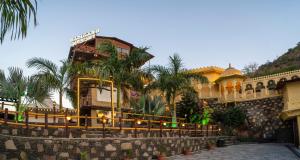 a building with palm trees in front of it at BADIGARH RESORT - Udaipur in Thūr