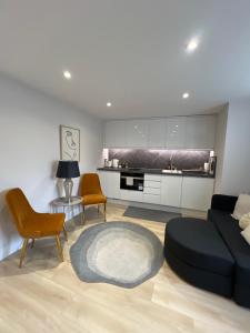 a living room with a couch and chairs and a kitchen at Brand New One Bedroom Apartment in Hendon
