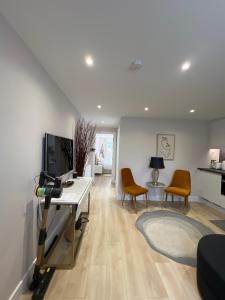 a living room with a desk and a tv and chairs at Brand New One Bedroom Apartment in Hendon
